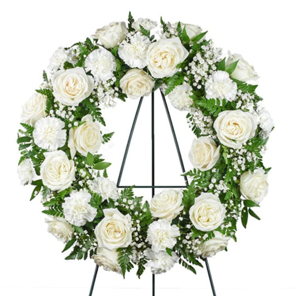 White rose and carnation wreath on a black easel