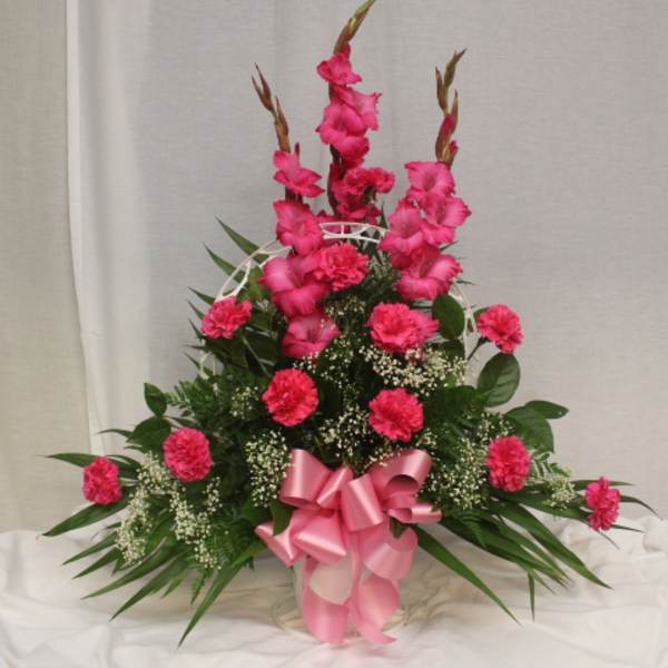 Tall pink floral arrangement with a ribbon bow in a basket