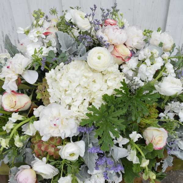 Large white floral arrangement with pale pink roses and purple accents