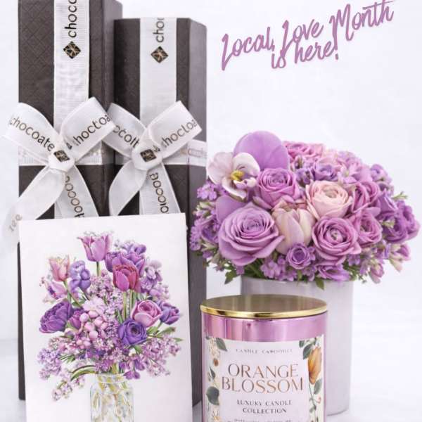 Gift set with purple flowers, chocolate boxes, and a pink candle