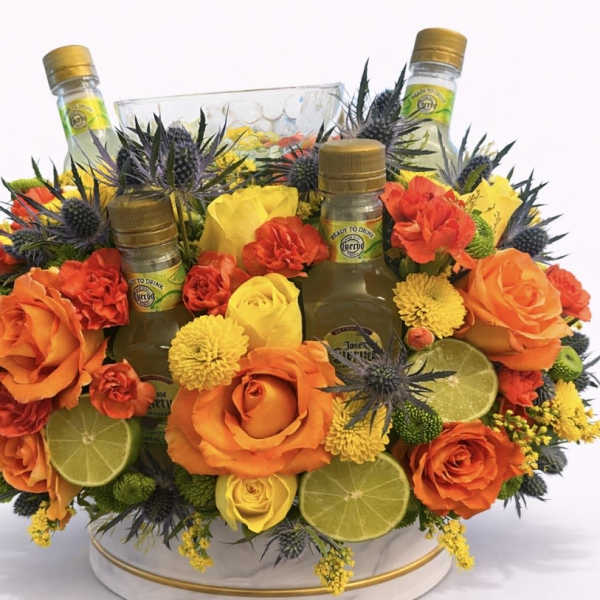 Orange and yellow floral arrangement with three mini liquor bottles and lime slices