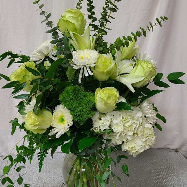 White and pale green floral arrangement in a glass vase