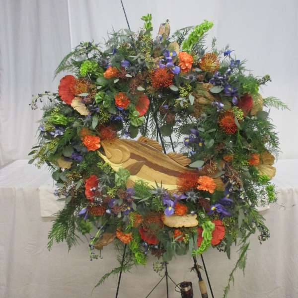 Large floral wreath on a stand with orange, purple, and green blooms