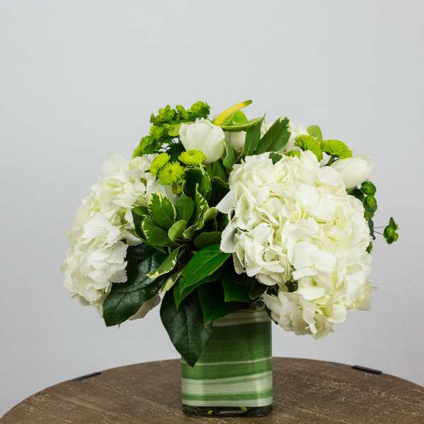 White hydrangeas and green flowers in a striped glass vase