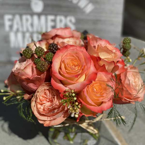 Peach and coral roses arranged in a glass vase