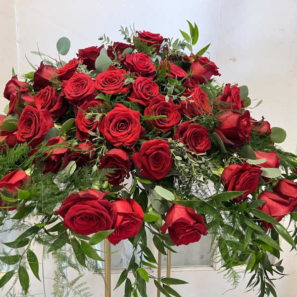 Large arrangement of red roses with greenery on a stand