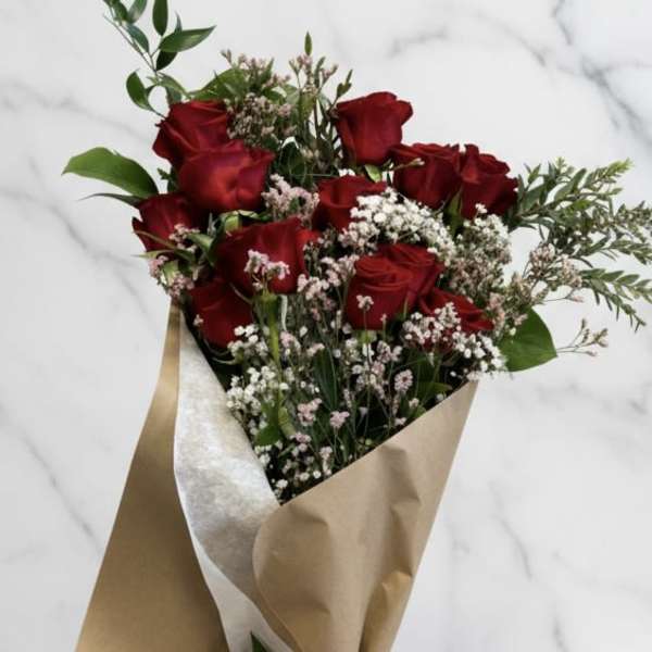 Bouquet of red roses with baby's breath in brown paper wrap