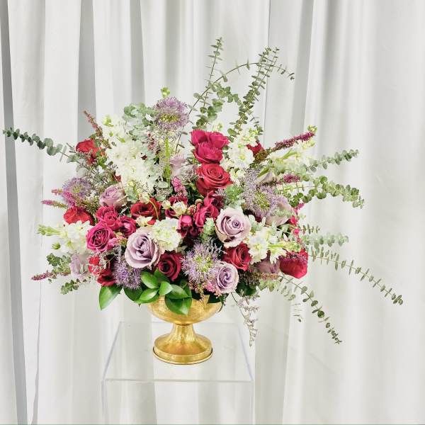 Mixed bouquet of roses and white blooms in a gold pedestal vase