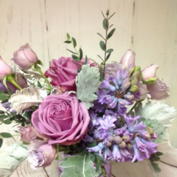 Lavender and pink roses with purple hyacinths in a purple glass vase