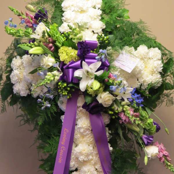 Standing white floral spray with purple ribbon and mixed blooms