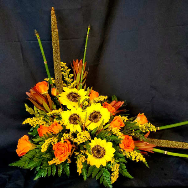 Orange roses and yellow sunflowers in a low floral arrangement