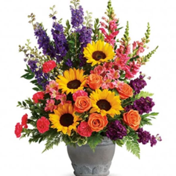 Colorful bouquet with sunflowers, roses, and purple spikes in a gray vase