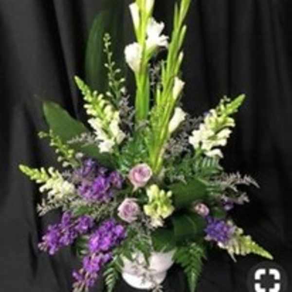 Tall floral arrangement with white and purple blooms in a white vase