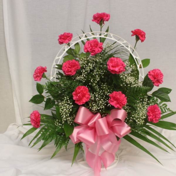 Pink carnations in a white basket with a pink ribbon