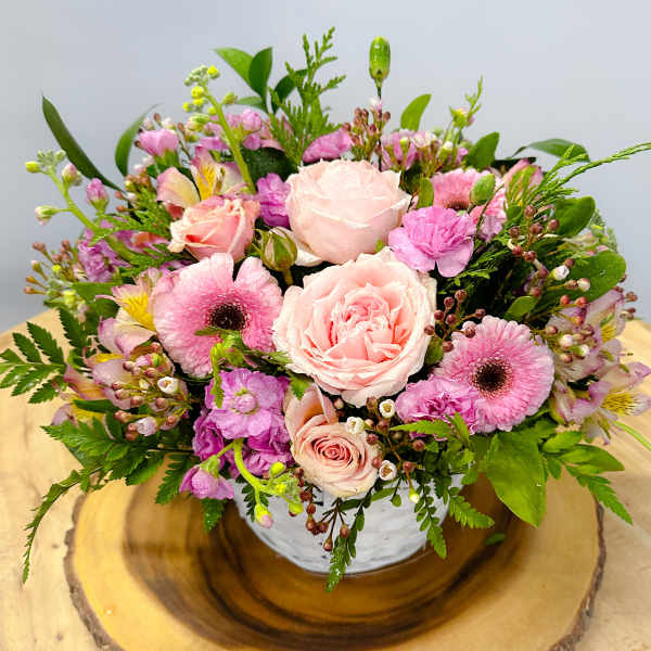 Pink roses and mixed blooms arranged in a white bowl vase