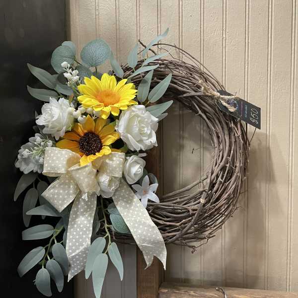 Floral wreath with yellow and white flowers and a large ribbon
