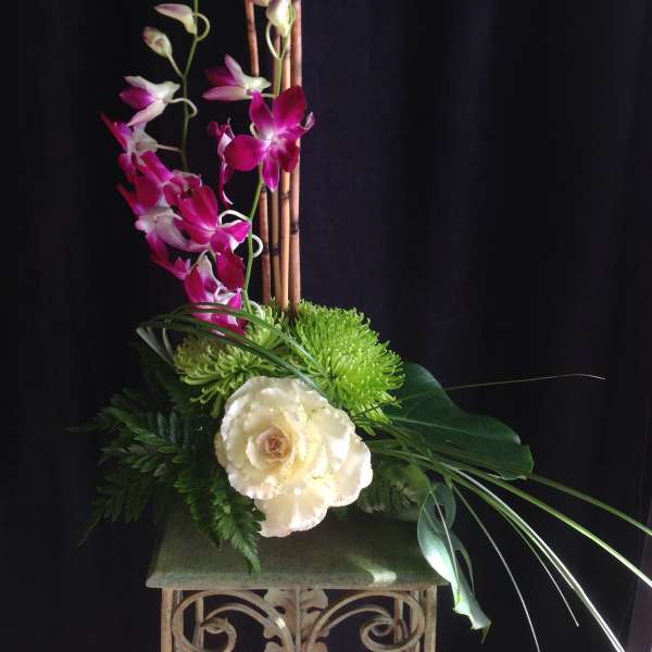 Tall floral arrangement with pink orchids, green chrysanthemums, and a white cabbage rose