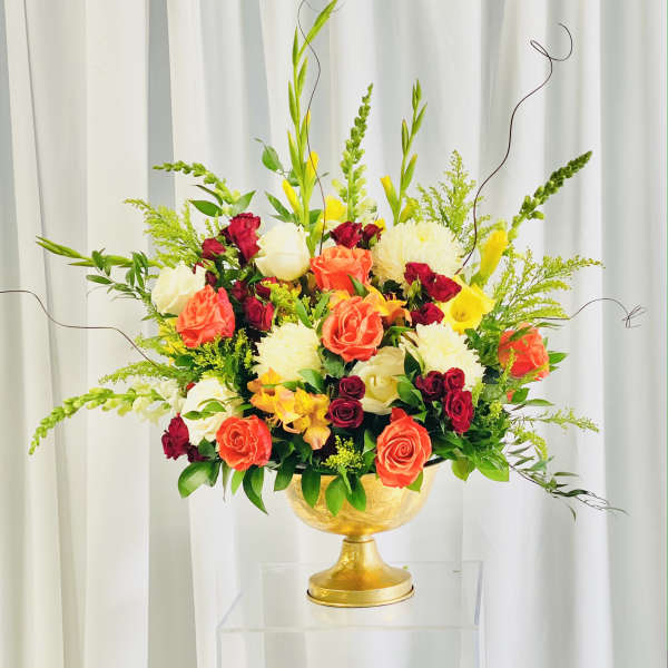 Mixed bouquet of roses and white blooms in a gold pedestal vase