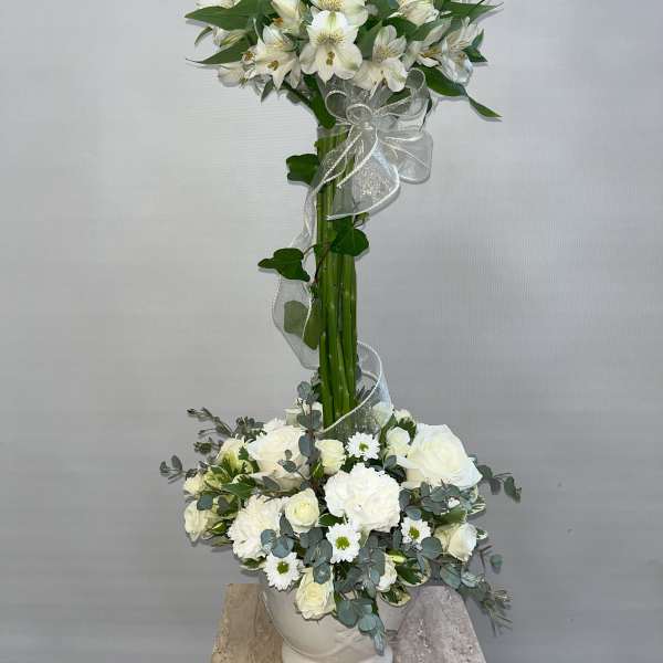 Tall white floral arrangement with a lower white bouquet in a vase