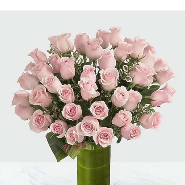 Pink roses arranged in a tall green glass vase