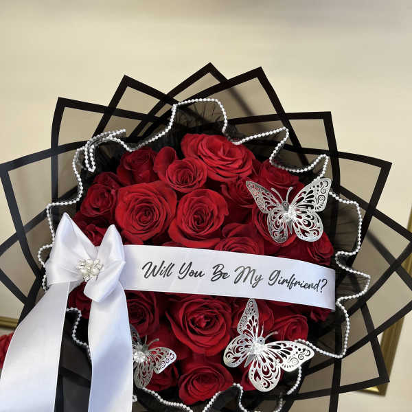 Bouquet of red roses with a white ribbon and butterfly decorations