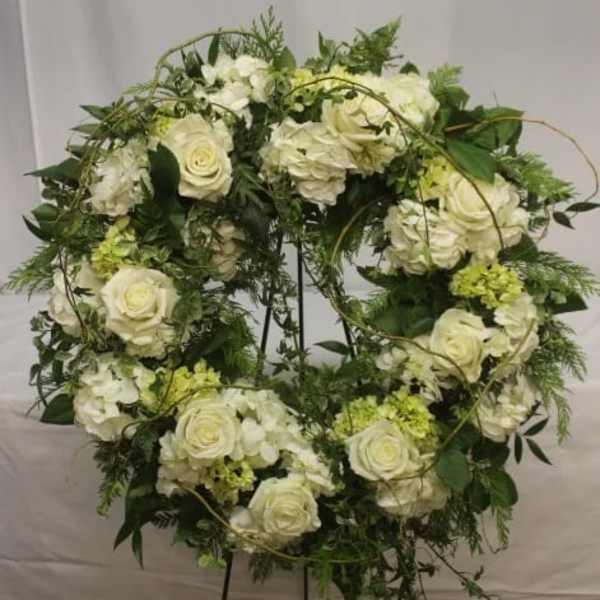 White rose and hydrangea wreath on a black stand