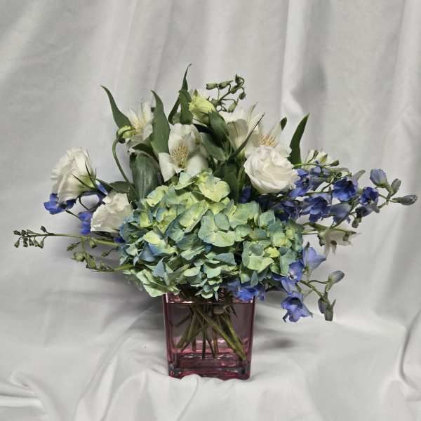 Blue hydrangea and white flowers in a pink glass vase