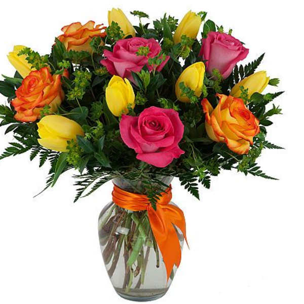 Bouquet of pink, yellow, and orange roses in a glass vase with an orange ribbon