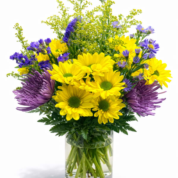 Yellow and purple flowers arranged in a clear glass vase