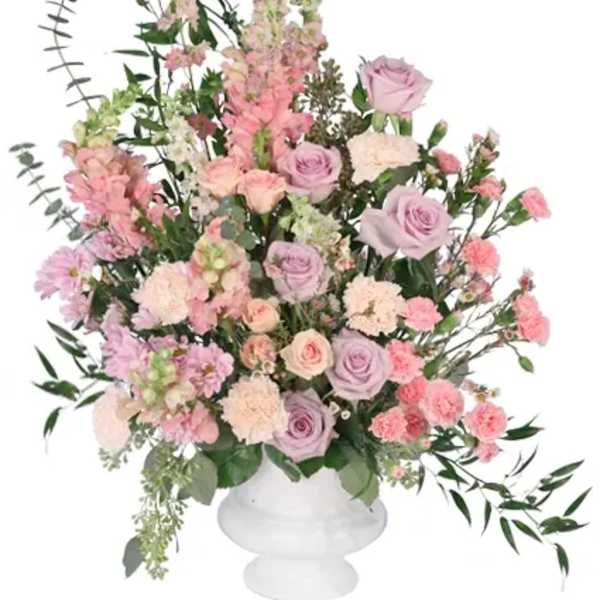 Large pastel floral arrangement in a white pedestal vase