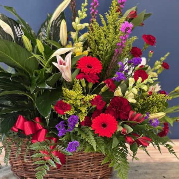 Mixed flower arrangement in a wicker basket with red and white blooms