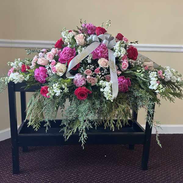 Large pink and white floral spray with roses on a black stand