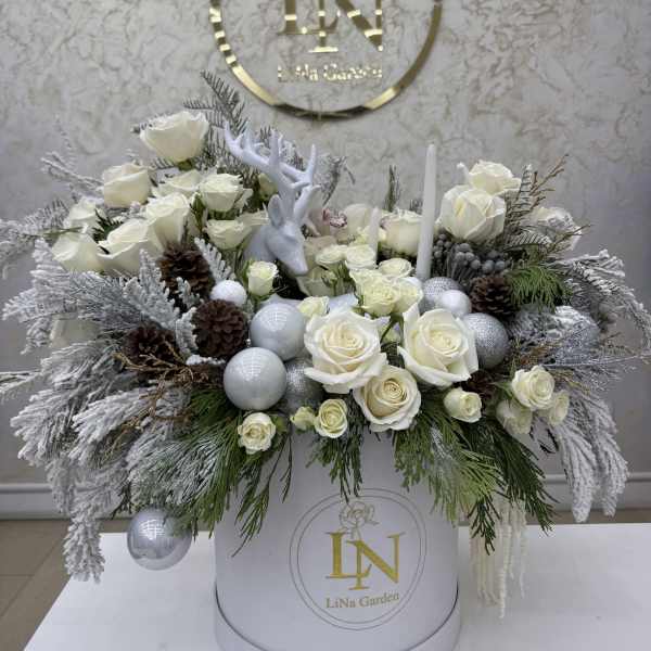 White rose arrangement in a round box with silver ornaments and pinecones