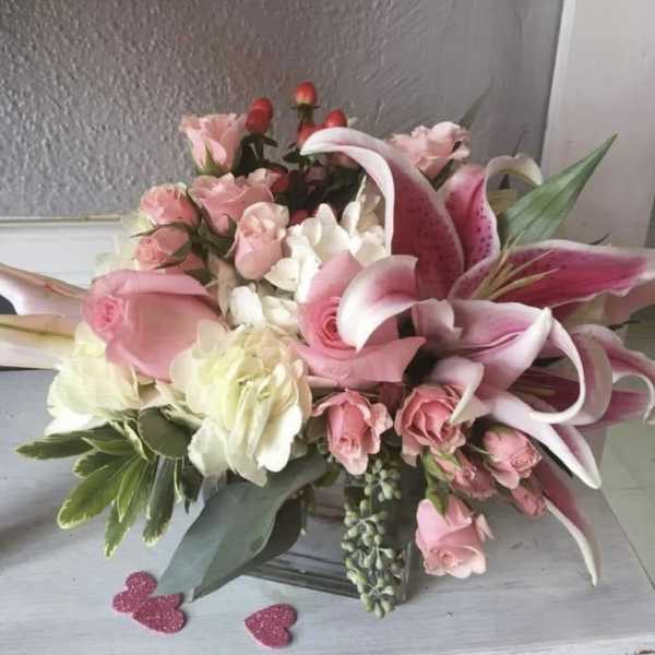 Pink lilies and roses arranged in a glass vase