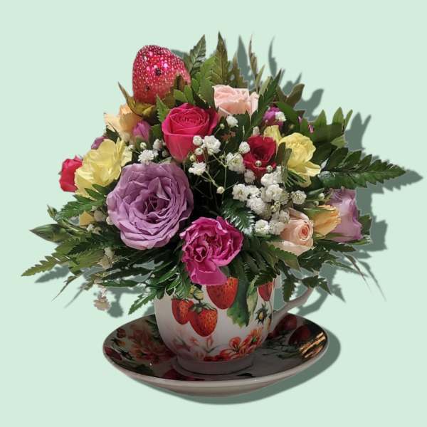Mixed roses in a strawberry-patterned teacup on a saucer