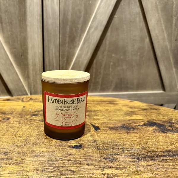Amber candle jar with a wooden lid on a rustic table