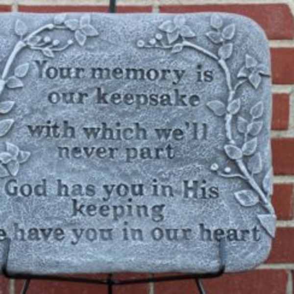 Memorial plaque with engraved text and vine border on a brick wall