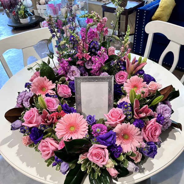 Round floral wreath with pink and purple blooms around a center frame