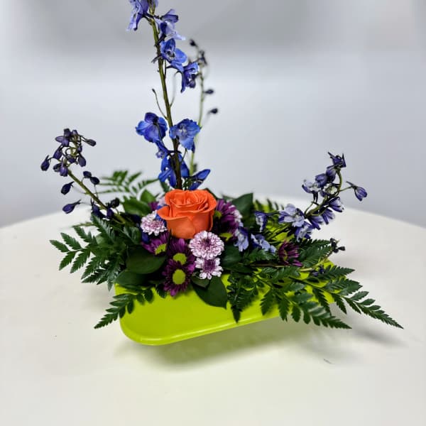 Orange rose and purple flowers in a lime-green tray