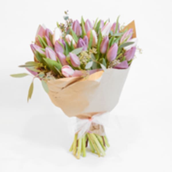 Bouquet of pink and lavender tulips wrapped in tan and white paper