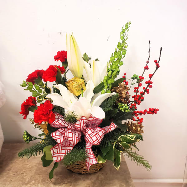 Holiday basket arrangement with white lilies, red carnations, and a red-and-white bow