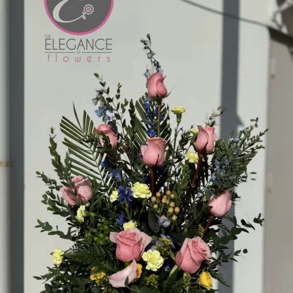 Tall arrangement of pink roses and mixed accent flowers in a vase