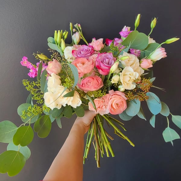 Handheld bouquet of pink and cream roses with eucalyptus