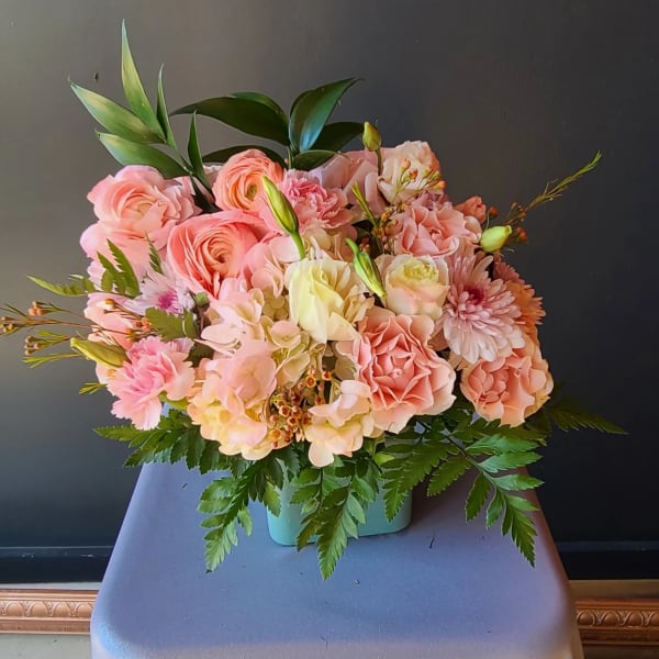 Pink and peach floral arrangement in a turquoise container
