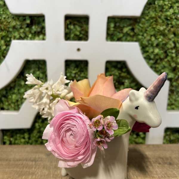 Pink and peach flowers arranged in a unicorn-shaped ceramic planter