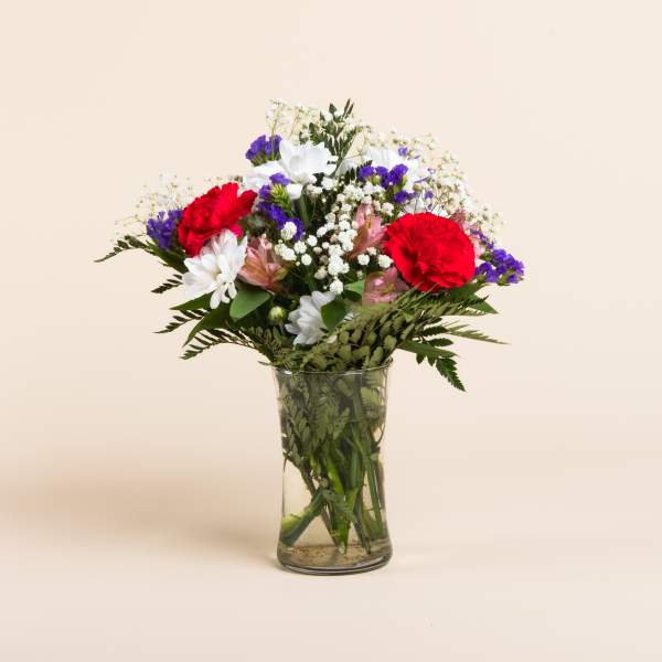 Mixed bouquet of red, white, and purple flowers in a clear glass vase