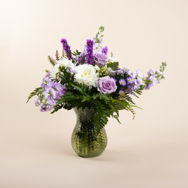 Lavender and white flower arrangement in a textured glass vase