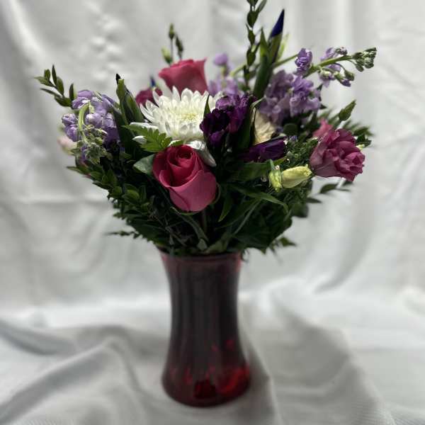 Mixed bouquet of pink, white, and purple flowers in a red vase