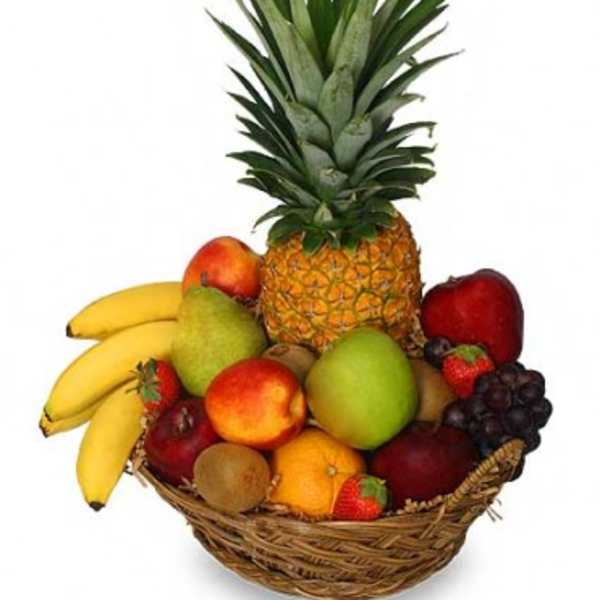 Wicker basket filled with assorted fresh fruits topped with a whole pineapple