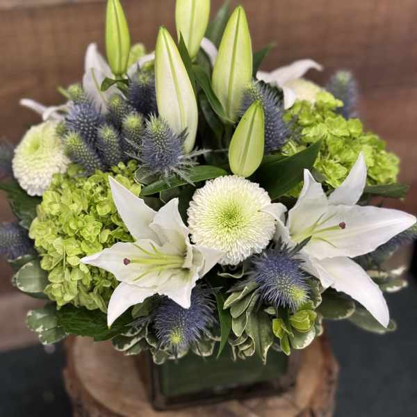 White lilies and green hydrangeas arranged in a square vase